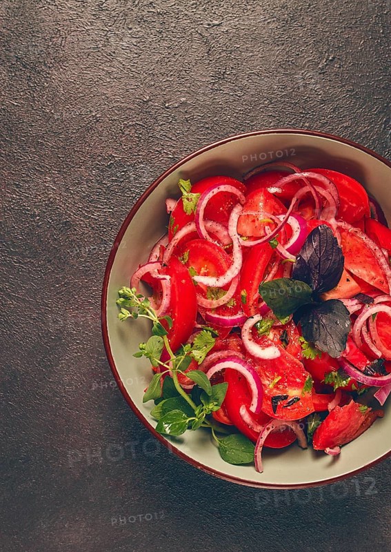 Fresh tomato salad, with red onion, spices and herbs, top view, close-up, homemade