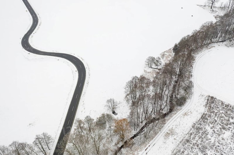 Aerial view of a winding country road and a stream in the snow, between Eppendorf and Leubsdorf, Central Saxony, Germany, Europe
