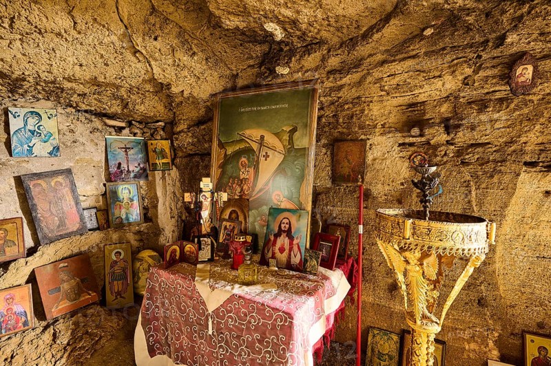 Interior view of a rock cave with an altar decorated with numerous religious pictures and icons, as well as a golden baptismal font, rock church of Agios Nikolaos, Oasis Beach, Kallithea, Rhodes, Dodecanese, Greek Islands, Greece, Europe