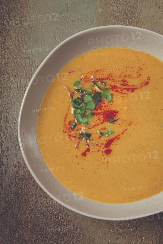 Pumpkin cream soup, in a white bowl on a textured background, top view, homemade, no people, rustic style