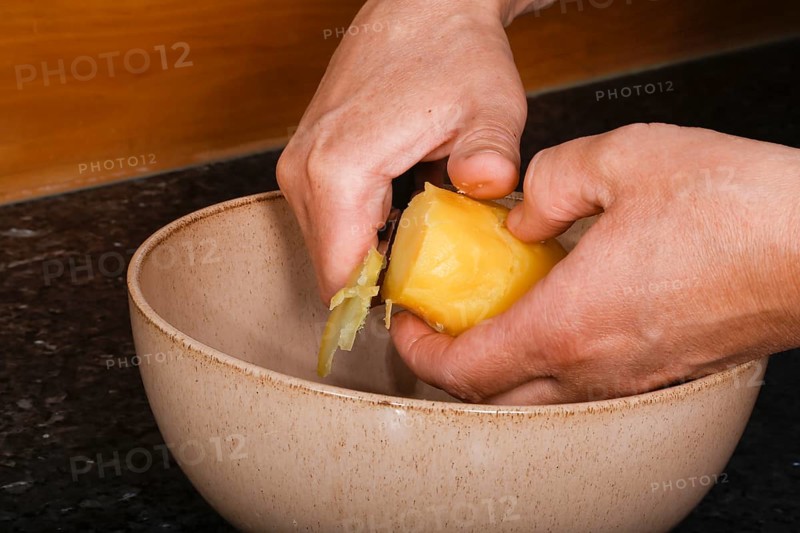 Swabian cuisine, preparation of Swabian potato salad with Stuttgarter Leberkäs in a horseradish-mustard coating, cutting boiled potatoes, grating, jacket potato, grandmother's kitchen, regional, home cooking, typical Swabian, salad bowl, knife, men's hands, traditional cuisine, food photography, studio, Germany, Europe