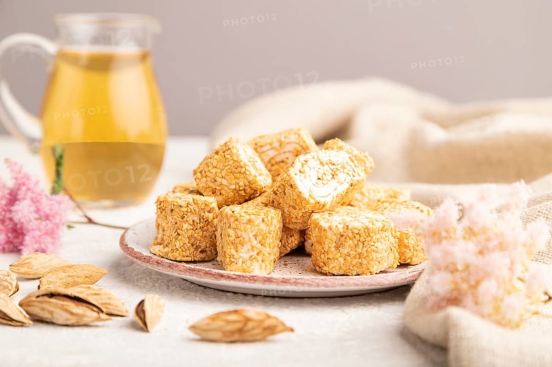 Traditional turkish delight (rahat lokum) with glass of green tea on a gray concrete background and linen textile. side view, selective focus, close up