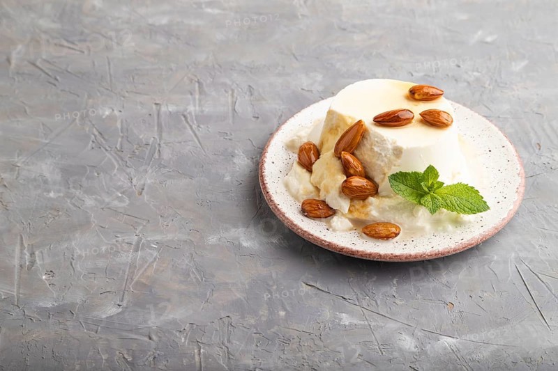 Ricotta cheese with honey and almonds on gray concrete background. side view, copy space