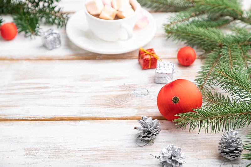 Christmas or New Year frame composition. Decorations, red balls, cones, fir and spruce branches, cup of coffee, on a white wooden background. Side view, copy space