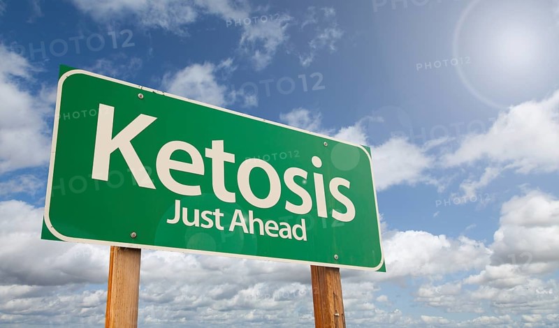 Ketosis just ahead green road sign over clouds and blue sky