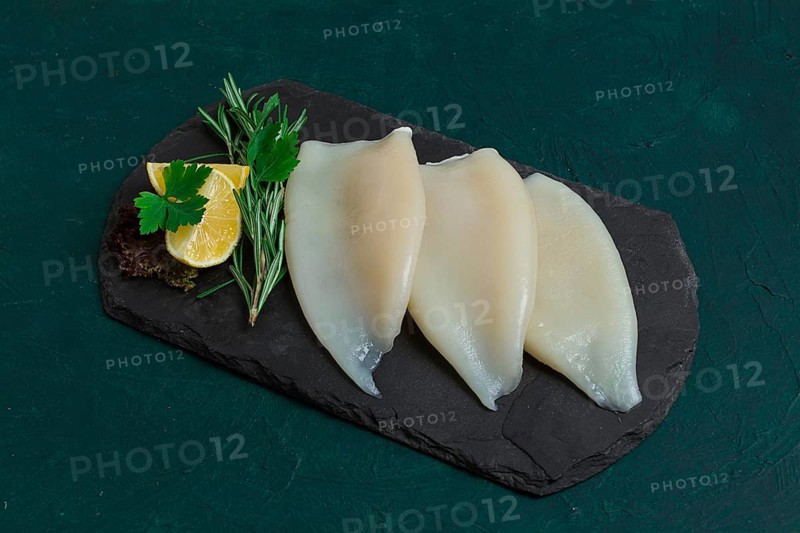 Fresh squid body, raw, three carcasses, top view, on black slate, no people