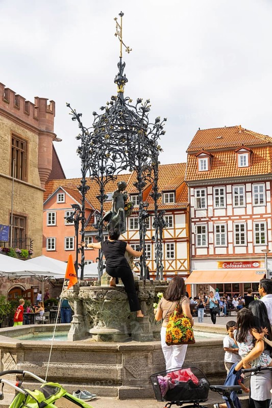 The Gänseliesel fountain is a market and ornamental fountain on the market square in front of the Old Town Hall in the city centre of Göttingen in Lower Saxony. The fountain with a Gänseliesel as a fountain figure was erected in 1901 and is considered a landmark of the city. Colloquially, the whole fountain is known as the Gänseliesel. In Göttingen, it is an old custom for graduates to go to the Gänseliesel on the city's market square after the graduation ceremony. The graduates climb onto the stone frame of the fountain figure and bring flowers to the Gänseliesel and give her a symbolic kiss., Stadtbild Göttingen, Göttingen, Niedersachsen, Germany, Europe