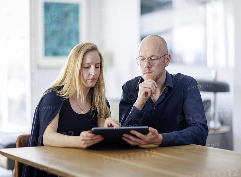 Symbolic photo. A woman and a man sit together at a table with a tablet and talk. Berlin, 13.08.2024