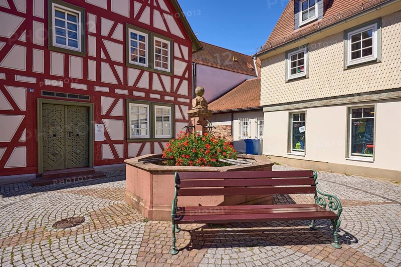 Running fountain with flowering geraniums and bench in Michelstadt, Odenwald, Odenwaldkreis, Hesse, Germany, Europe