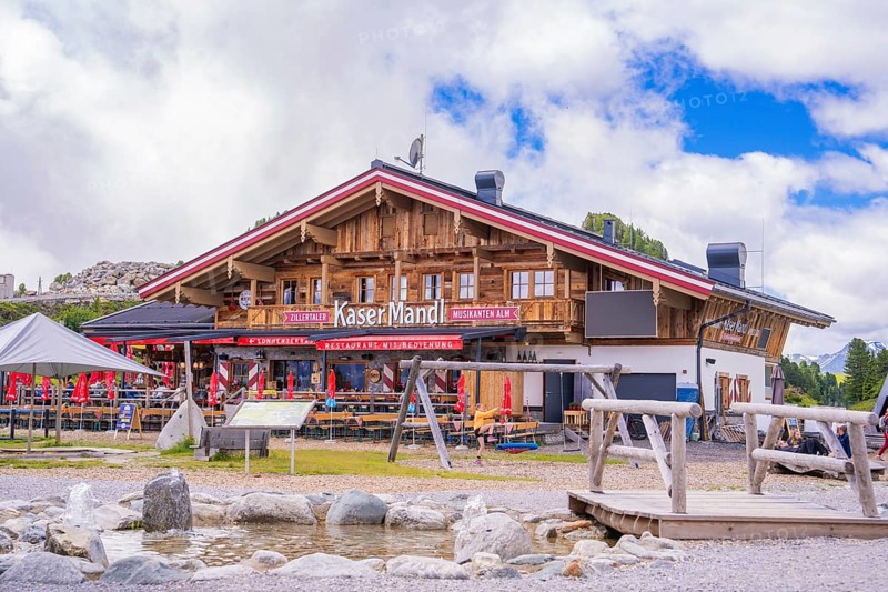 A rustic Alpine restaurant with wooden beams and outdoor seating against a mountain backdrop, Penken, Zillertal, Austria, Europe