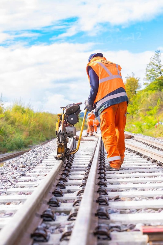 A worker with a machine on the railway tracks, working in the open air, rail welding, track construction Hermann Hessebahn, Calw, Black Forest, Germany, Europe