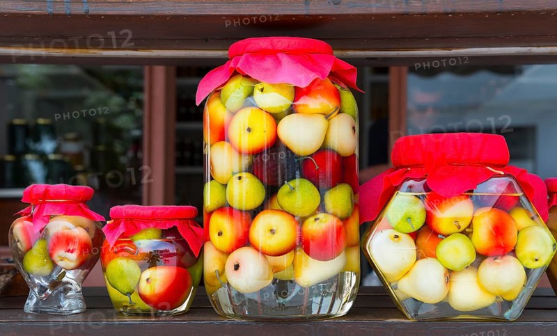 Colourful assorted glass jars with pickled fruit and red lids in front of a wooden backdrop, Portaria, Municipality of Volos, Pilio Mountains, Thessaly, Greece, Europe