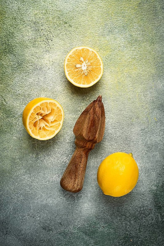 Wooden citrus reamer, manual lemon juicer, made of acacia wood, with citrus fruits on the table, top view