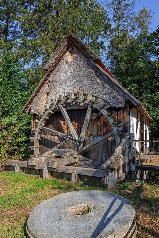 Millstone and 18th century watermill, water wheel in the recreated Kempen, Campine village at open air museum Bokrijk, Limburg, Flanders, Belgium, Europe