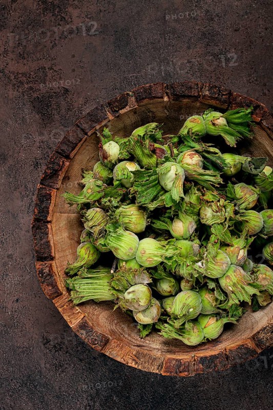 Fresh, green hazelnuts, close-up, in a wooden bowl, unpeeled, top view, no people