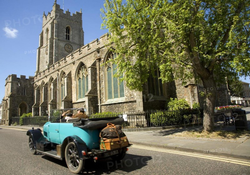 Classic veteran car passing Church of Saint Peter, Sudbury, Suffolk, England, United Kingdom, Europe