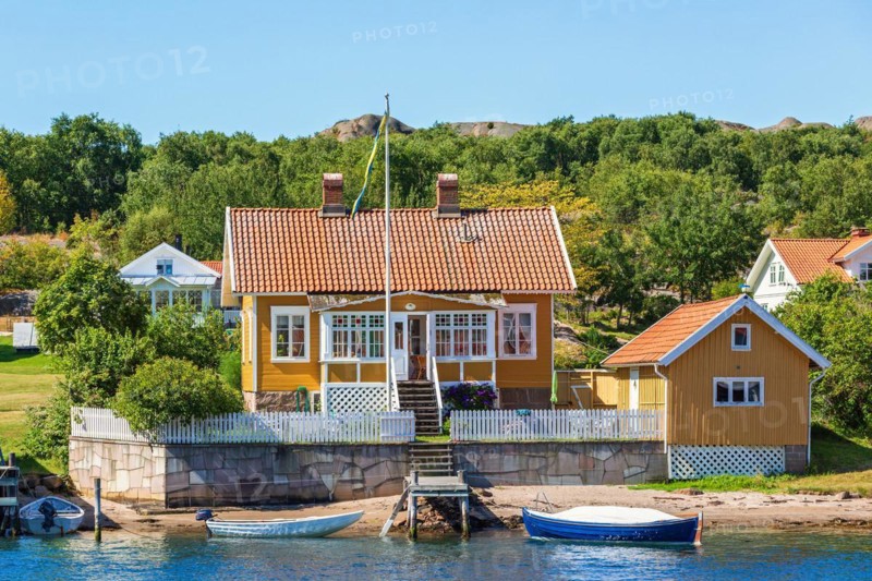 Idyllic summer cottage by a sea beach with a jetty and boats in the Swedish archipelago in the summer, Hamburgsund, Bohuslän, Sweden, Europe