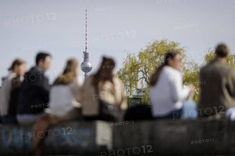 People sitting in the sun on the banks of the Spree in Berlin, 27 March 2024, with the Berlin television tower in the background. According to weather forecasts, highs of around 22 degrees are expected at Easter
