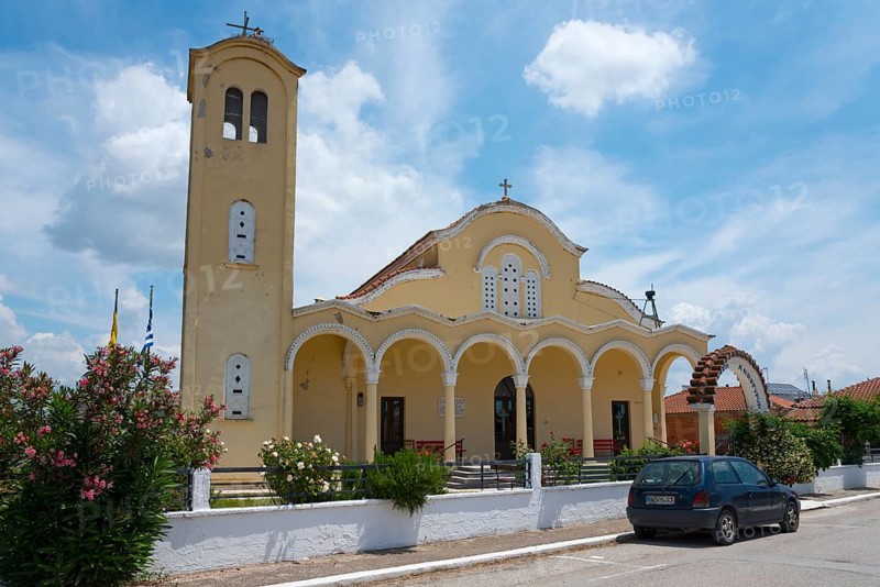 Church with yellow facade and bell tower under a blue sky, surrounded by flowers and a parked car, Holy Church of Agioi Anargyro, Stork Village Poros, Feres, Alexandroupoli, Evros, Eastern Macedonia and Thrace, Greece, Europe