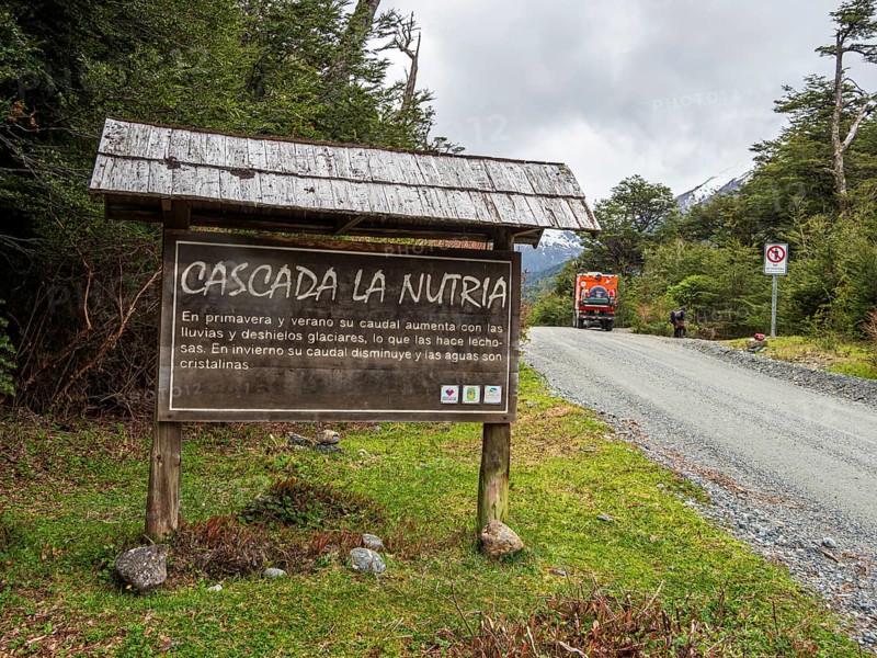 Information board at waterfall Cascada La Nutria, overlander truck on gravel road, Valle Exploradores, Patagonia, Chile, South America