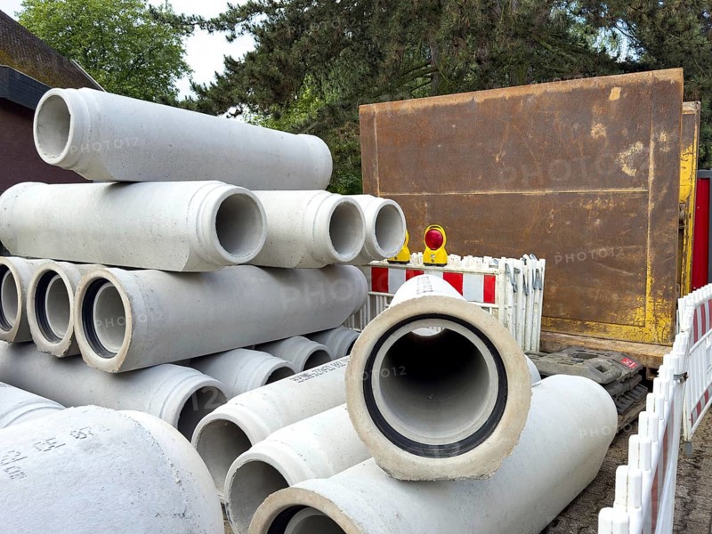 Several concrete pipes stored at the roadside Concrete pipes for sewer construction Laying of sewer during road construction, in the background sheet pile wall for excavation pit stabilisation, Germany, Europe