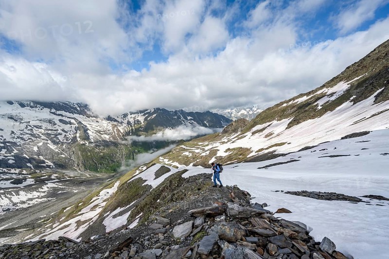 Mountaineer on hiking trail with snow, mountain landscape with summit Hoher Weißzint and Hochsteller with glacier Schlegeiskees, Berliner Höhenweg, Zillertal Alps, Tyrol, Austria, Europe