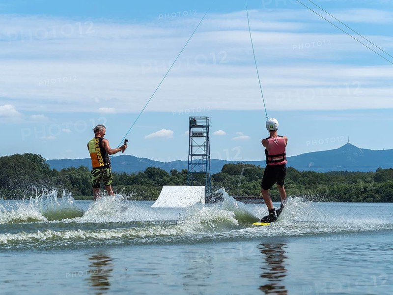 Water sports with wakeboard, two men riding side by side in the lake, camera in hand, water skiing and summer holiday, Stráž pod Ralskem, Czech Republic, Europe