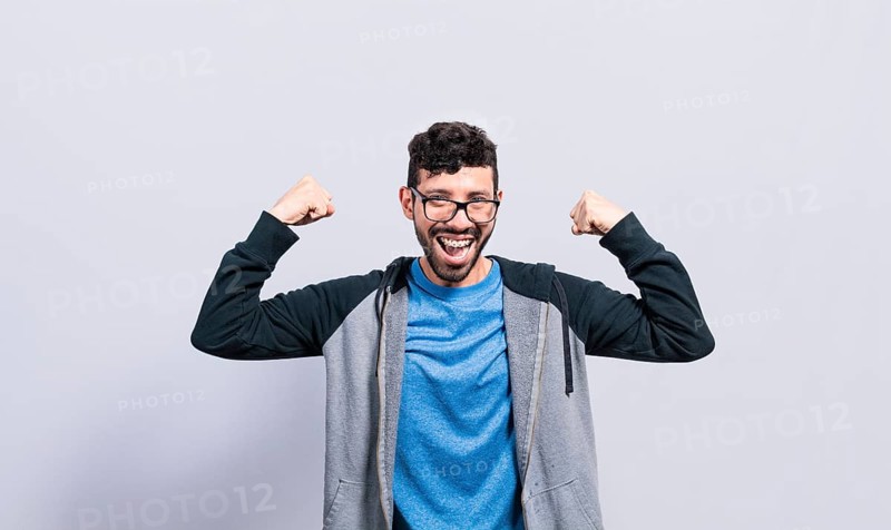 Young man with happy face raising arms in victory gesture isolated. Winner person celebrating victory raising arms isolated
