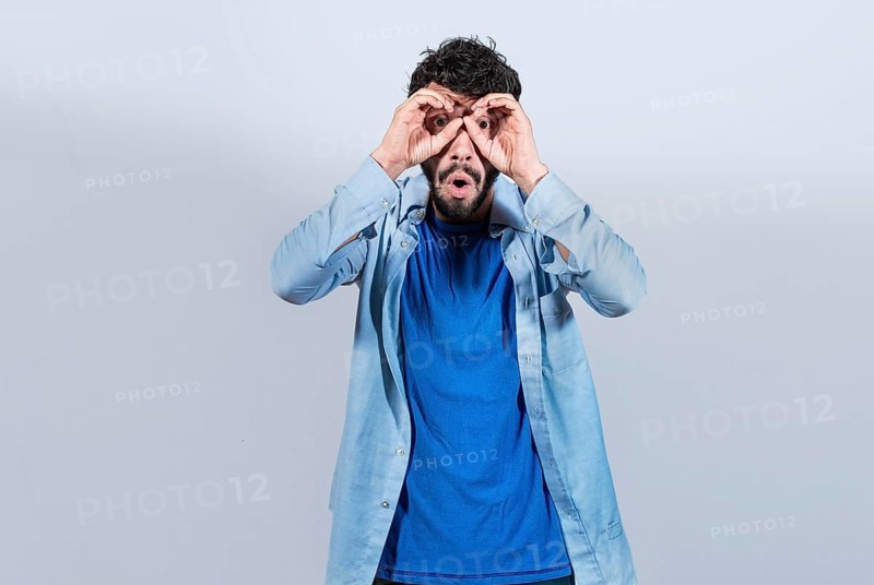 Curious man making binoculars gesture isolated. Guy making binoculars gesture isolated. Man making binoculars gesture