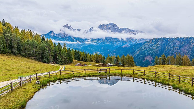 Alpine meadow and Wuhnleger Weiher, in the background the peaks of the rose garden, shrouded in fog, drone shot, Dolomites, Autonomous Province of Bolzano, South Tyrol, Italy, Europe