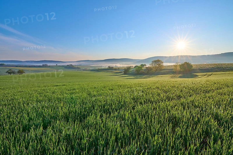 A picturesque sunrise over a wide green field and a gentle hilly landscape, Mönchberg, Mltenberg, Spessart, Bavaria, Germany, Europe