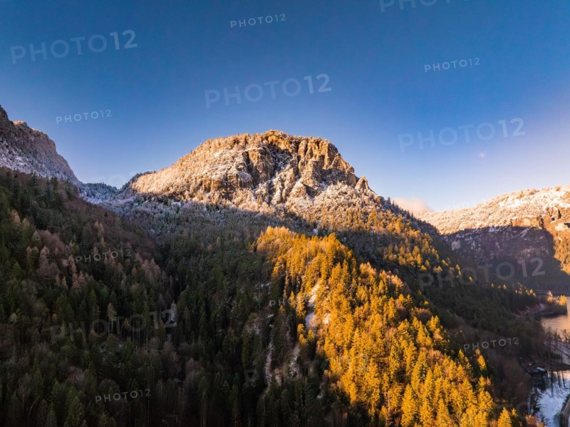 Sunrise illuminates the snow-covered peak and autumnal forest, Bad Reichenhall, Bavaria, Germany, Europe
