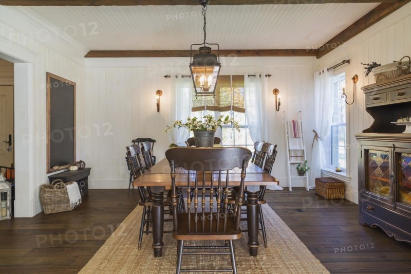 Brown stained pine wood antique reproduction style dining table with high back chairs in dining room with rug and dark brown larch wood floorboards inside country style home, Quebec, Canada, North America