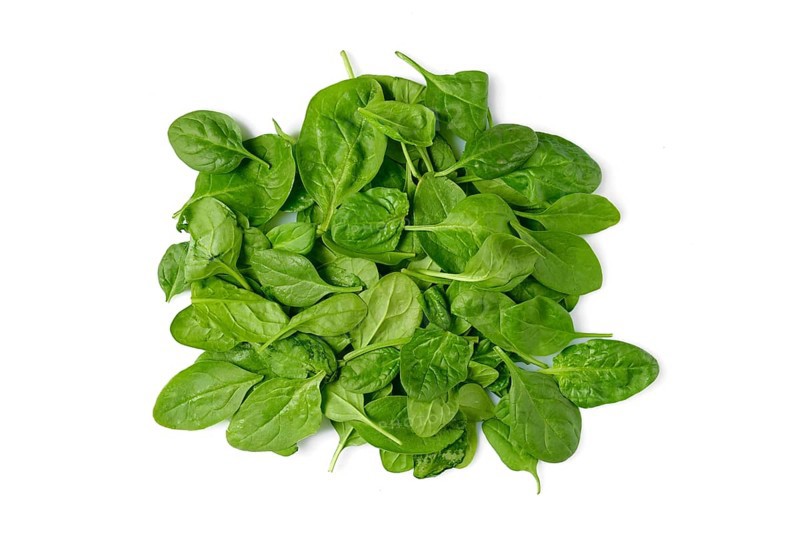 A pile of fresh spinach leaves on a clean white background, ready for use in salads, smoothies, or various cooking dishes, emphasising healthy eating and nutrition