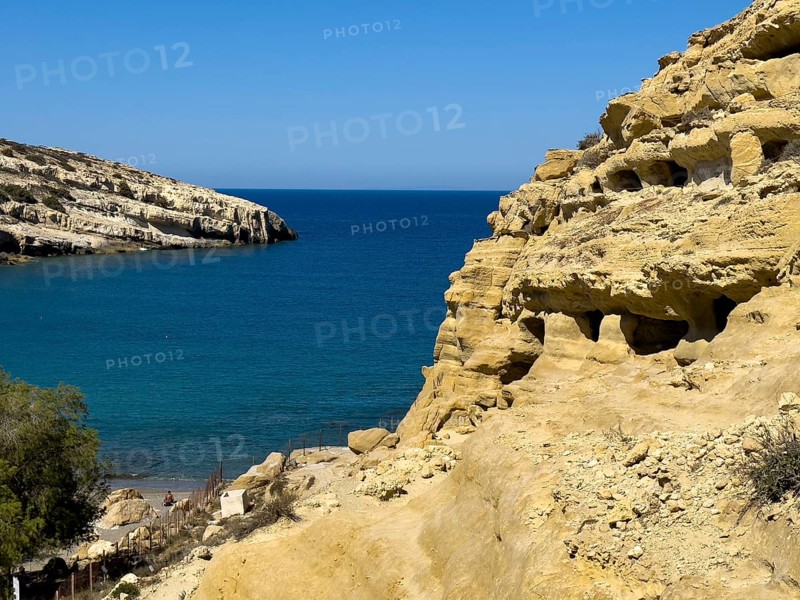 View of entrances of caves in sandstone rocks of former Roman necropolis with sandstone caves carved into sandstone Cave tombs Grottoes in rocks on the north side of Matala Bay, in the 60s and 70s hippie caves Caves for dropouts and hippies today excursion destination on the south coast of Crete island, left at the edge of the picture Libyan Sea Mediterranean, Matala, Crete, Greece, Europe