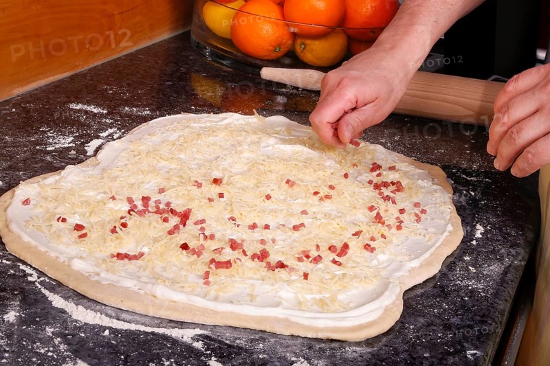 Swabian cuisine, preparation of savoury yeast plait with smoked meat, salty wreath bread, yeast yeast dough pastries, raw yeast dough sprinkled with diced bacon, grated cheese, sour cream, grandmother's cooking, regional, home cooking, typical Swabian cuisine reinterpreted, traditional cuisine reinterpreted, men's hands, food photography, studio, Germany, Europe