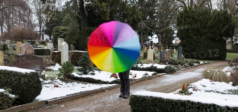 Man with colourful umbrella in grey weather between graves, Riesa cemetery, Saxony, Germany, Europe