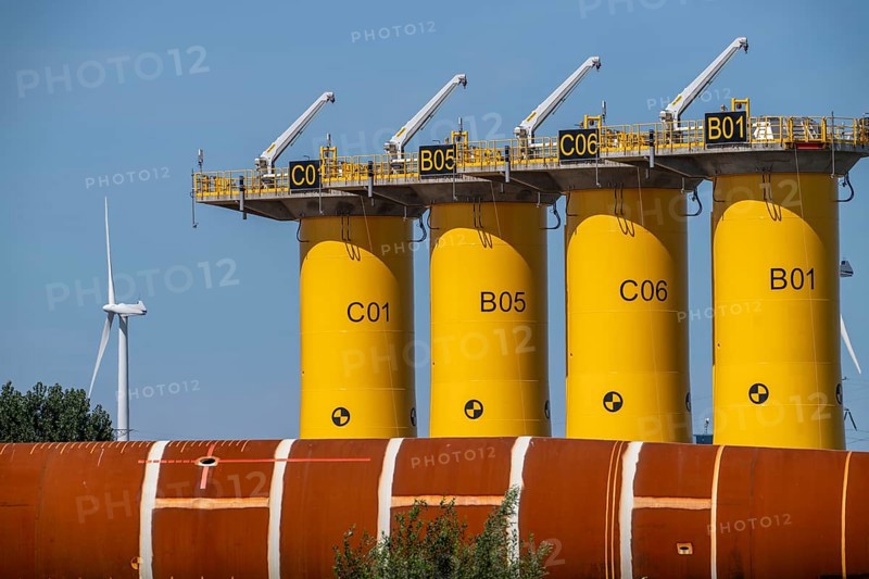 Transhipment centre for offshore wind turbines, which are transported here by the manufacturer and then shipped by special ships to the construction sites of the wind farms in the North Sea, here, yellow, so-called Transition Pieces Jackets, which are mounted on the monopile foundations driven into the seabed, on which the actual wind turbine is then mounted, in the port area of Vlissingen-Oost, Netherlands