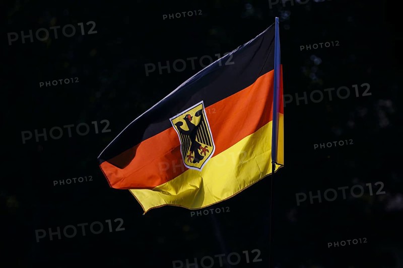 Symbolic photo. The national flag of the Federal Republic of Germany with a federal eagle fluttering in the wind against the light. Berlin, 21 August 2024
