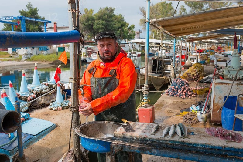 Fishermen standing in the harbour, dressed in orange, ready to sell fish, busy atmosphere at the pier, Nea Kios, Argolis, Peloponnese, Greece, Europe
