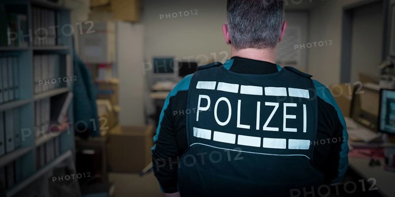 A police officer in uniform stands in an office with screens and files, symbolic image search, Germany, Europe