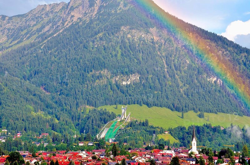 View over Oberstdorf with rainbow, behind it the Schattenberg with Schattenbergschanze, Oberallgäu, Bavaria, Germany, Europe