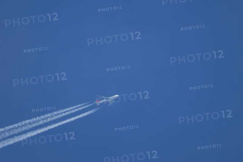 Boeing 747 jumbo jet aircraft flying across a blue sky with a vapour trail or contrail behind, England, United Kingdom, Europe