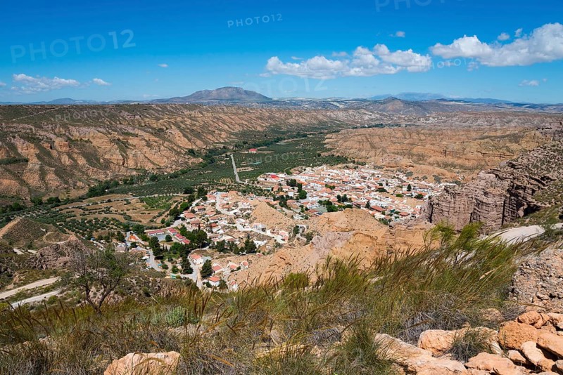A village with white houses and red roofs, nestled in a dry, mountainous desert landscape under a blue sky, Gorafe, Guadix, Granada, Andalusia, Spain, Europe