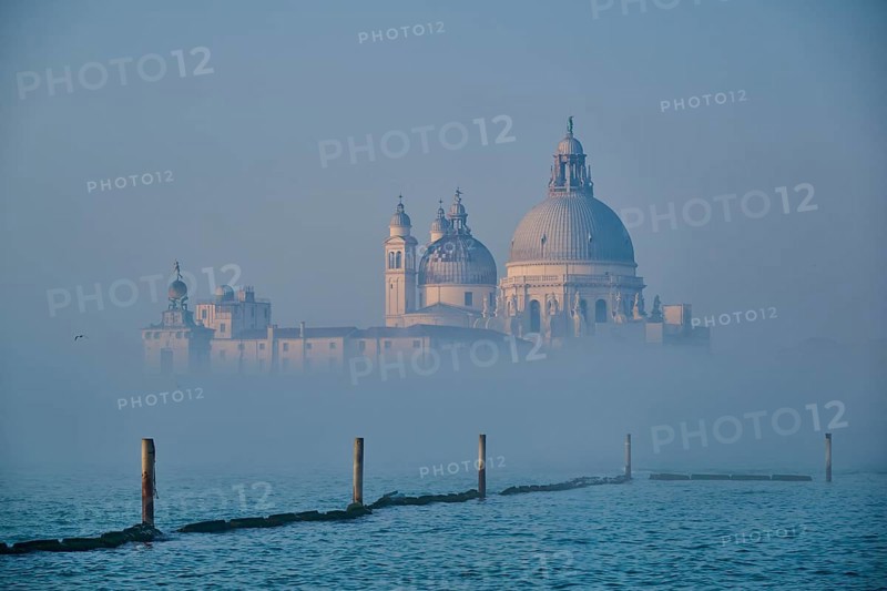 View from 'Colonna di San Marco e San Teodoro' on church 'Basilica di Santa Maria della Salute' on a foggy morning at sunrise in Venice in winter, Italy, Europe