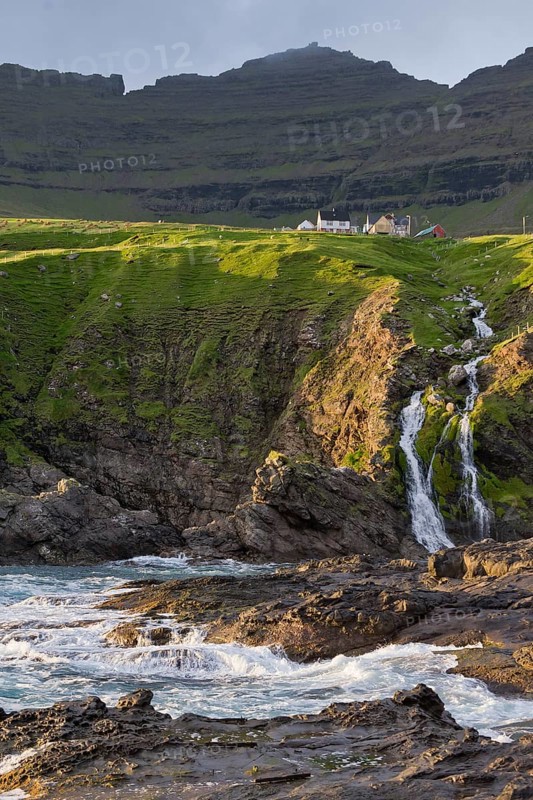 Houses against a mountain backdrop, rocky coast, sea, surf, Vidareidi, Vidoy Island, Viðareiði, Viðoy Island, Faroe Islands, Denmark, Europe