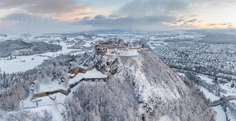 Aerial view, panorama of the snow-covered Hegau volcano Hohentwiel with Germany's largest castle ruin on a cold winter morning, in front of sunrise, surrounded by frosty trees in a winter landscape, on the horizon the neighbouring Hegau volcano Hohenkrähen, district of Constance, Baden-Württemberg, Germany, Europe