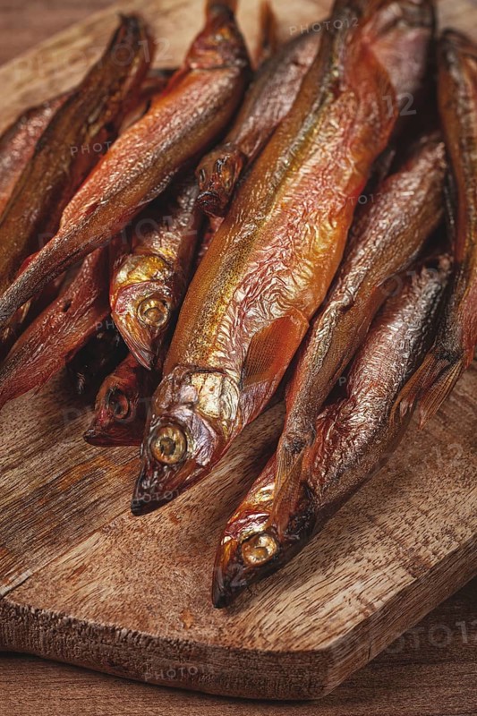 Cold smoked capelin, on a wooden chopping board, no people