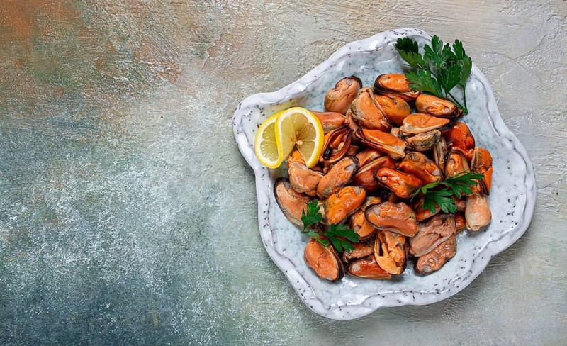 Mussels no shell, boiled, mussels, peeled, in a bowl, with lemon and parsley, Chilean mussels, top view, no people