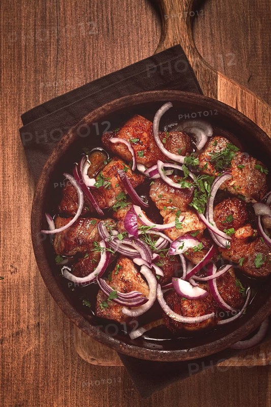 Fried meat, pork kebab, ketsi in a clay pan, with red onions and herbs, homemade, no people